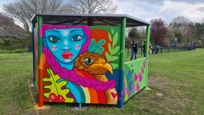 Photo of rain shelter for teenagers with brightly coloured decorative "graffiti" showing a blue face and a bird